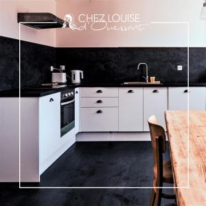 a kitchen with white cabinets and a black wall at Le gite de Louise in Lampaul