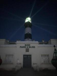 a lighthouse sitting on top of a white building at Le gite de Louise in Ouessant