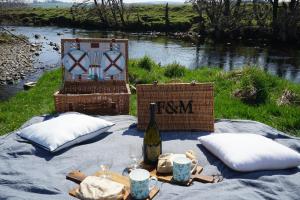 a picnic table with a bottle of wine and two chairs at Elishaw Farm Holiday Cottages in Otterburn