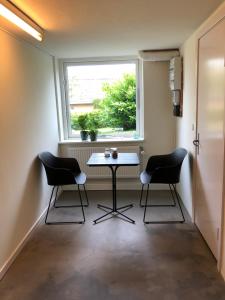 stół i 2 krzesła w pokoju z oknem w obiekcie Guesthouse Dybbøl, Sønderborg w mieście Sønderborg