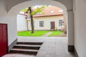 une arche menant à une cour avec un arbre dans l'établissement Poarta Schei 18, à Braşov