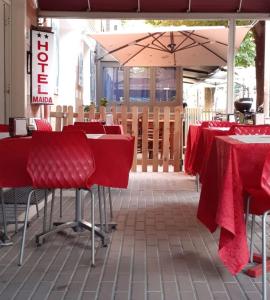un ristorante con tavoli e sedie rossi e un ombrellone di HOTEL MAIDA a Follonica