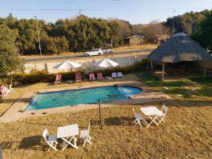 a swimming pool with chairs and umbrellas next to a car at Ikhutseng guesthouse and spa in Pretoria