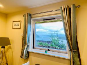 een raam met uitzicht op de oceaan bij Hazelmount Self-Catering Cabin in Portree