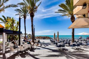 a restaurant with palm trees and the beach at Moderno Apartamento SCANDIC, Playa Del Cura in Torrevieja