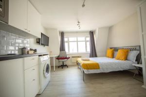 a bedroom with a bed with yellow pillows and a kitchen at X Farringdon Apartments in London