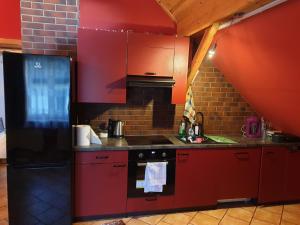 kuchnia z czerwonymi szafkami i czarną lodówką w obiekcie Dom na Wzgórzu w Andrychowie