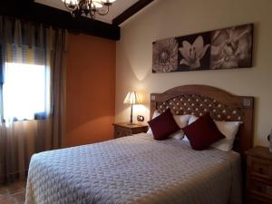 Un dormitorio con una cama con almohadas rojas y una ventana en Sierra Palomera, en Camañas