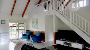 a living room with blue chairs and a staircase at Pitcairn House in Burnt Pine
