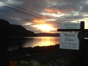 a sign for a roman house next to a lake at Rowan House B&B Rooms & A Self Catering Apartment in Lochgoilhead