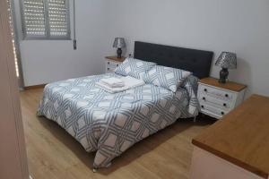 a bedroom with a bed and two night stands and a table at Apartamento Lalín Centro ll in Lalín