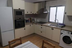 a kitchen with white cabinets and a sink and a dishwasher at Apartamento Lalín Centro ll in Lalín