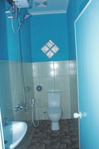 ein blaues Badezimmer mit WC und Waschbecken in der Unterkunft Omah Sundak Homestay in Tepus