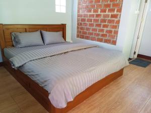 uma cama num quarto com uma parede de tijolos em ก่อน-ใดใด อพาร์ทเม้นท์ em Ban Nong Ki