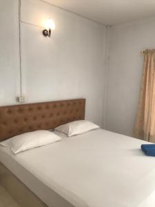 un letto con lenzuola bianche e testiera in una stanza di สวนไผ่รีสอร์ท a Ban Na