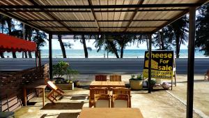 a table and chairs under a pavilion with the beach at Amy's beach apartments in Rayong