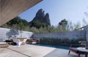 a backyard with a swimming pool and a stone wall at Yangshuo Sugar House in Yangshuo