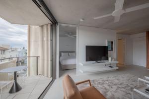 a living room with a bed and a tv on a wall at Hotel Ravesis in Sydney