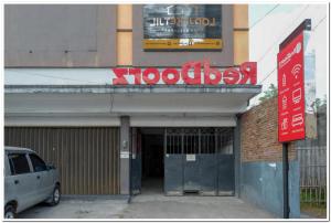 ein Auto, das vor einem Gebäude mit einem Schild parkt in der Unterkunft RedDoorz near Jogja Expo Center 2 in Yogyakarta