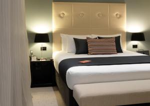 a bedroom with a large bed and two lamps at Sudima Auckland Airport in Auckland