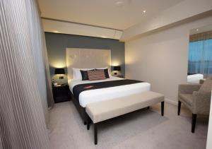 a bedroom with a king sized bed and a chair at Sudima Auckland Airport in Auckland