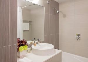 a bathroom with a white sink and a mirror at Sudima Auckland Airport in Auckland