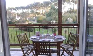 a table and chairs on a balcony with a view of a garden at T2 Antigua Ondres plage avec piscine et tennis in Ondres