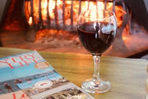 a glass of wine next to a magazine and a fireplace at Cheverells Farm, Kiku & Braeburn Cottage in Grabouw +37 photos