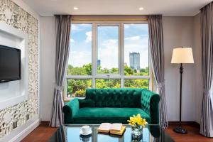 a living room with a green couch and a large window at Minerva Church Hotel in Hanoi