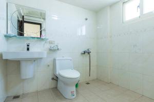 Un baño con inodoro, lavabo y espejo. en 實在玩家民宿, en Magong
