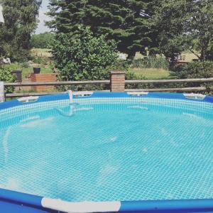 a large blue swimming pool with chairs and a fence at Bauernhofurlaub bei Familie Bokeloh in Kirchlinteln