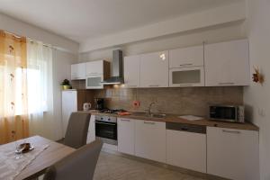 una cucina con armadi bianchi e un tavolo in legno con tavolo da pranzo di Apartment Car Marica a Šilo