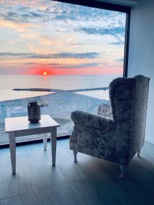 Maritimo Luxury ApartHotel في كونستانتا: غرفة معيشة مع كرسي وطاولة ونافذة