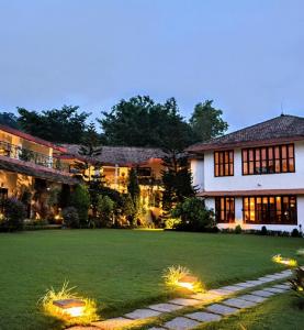 a large house with a lawn in front of it at Amritara Ambatty Greens Resort in Virajpet