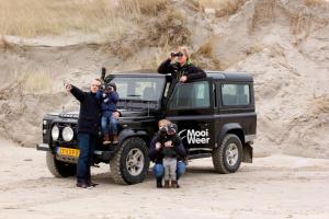 a group of people standing next to a jeep on the beach at Paal 8 Hotel aan Zee in West aan Zee