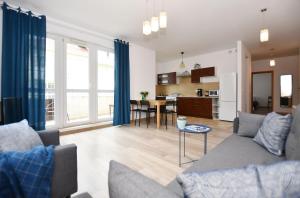 a living room with a couch and a table and a kitchen at MIZU Apartamenty - Bałtyk in Grzybowo