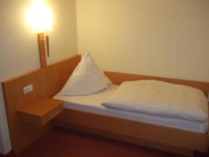 Una cama pequeña con una almohada blanca. en Hotel Rose, en Georgsmarienhütte