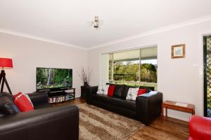 sala de estar con 2 sofás negros y TV de pantalla plana en Valley Haven 3 bedrooms close to the village en Kangaroo Valley