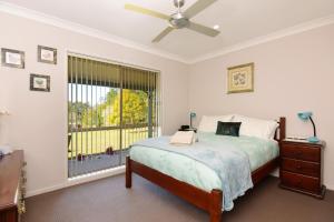 a bedroom with a bed with a ceiling fan and a window at Valley Haven 3 bedrooms close to the village in Kangaroo Valley