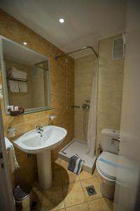 ein Badezimmer mit einem Waschbecken, einem WC und einem Spiegel in der Unterkunft Hotel Olympos in Pýrgos