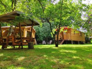 uma cabana de madeira num quintal com um gazebo em La Roulotte d'Emilie et son jacuzzi privé em Beurlay