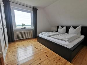 a bedroom with a bed and a large window at Moderne Ferienwohnung in ruhiger Lage in Neetze