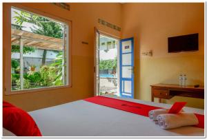 a bedroom with a bed and a window and a desk at RedDoorz @ Prawirotaman in Yogyakarta