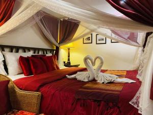 2 cigni sono seduti su un letto in una camera da letto di Tri Yaan Na Ros Colonial House a Chiang Mai Altre 193 foto