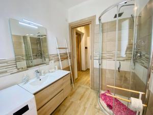 een badkamer met een wastafel en een glazen douche bij Le case di Helga in Budoni