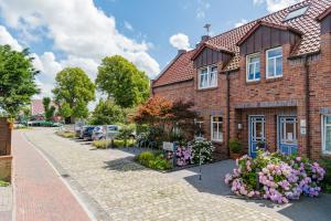 una casa di mattoni con dei fiori di fronte di Hotel am Fischerhafen a Ditzum