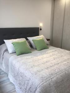 a white bed with two green pillows on it at Sol de Verano in A Coruña