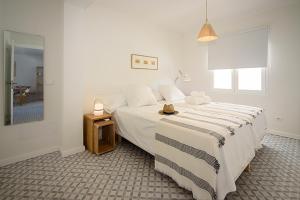 ein weißes Schlafzimmer mit einem großen Bett und einem Tisch in der Unterkunft BLAU Apartamento en Cala Galiota con vistas al mar in Colonia Sant Jordi