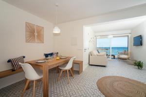 ein Wohnzimmer mit einem Tisch, Stühlen und Meerblick in der Unterkunft BLAU Apartamento en Cala Galiota con vistas al mar in Colonia Sant Jordi