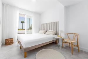 biała sypialnia z łóżkiem i krzesłem w obiekcie Bella Vista Puerto Banus apartment with sea views w Marbelli